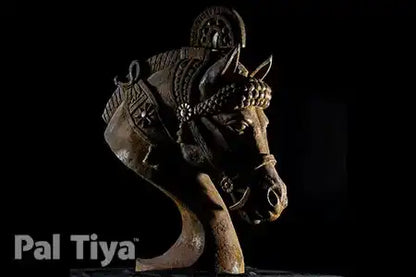 An ornate carved horse head sculpture in a dark metallic finish, shown against a solid black background with a 'Pal Tiya' brand logo in the bottom-left corner.